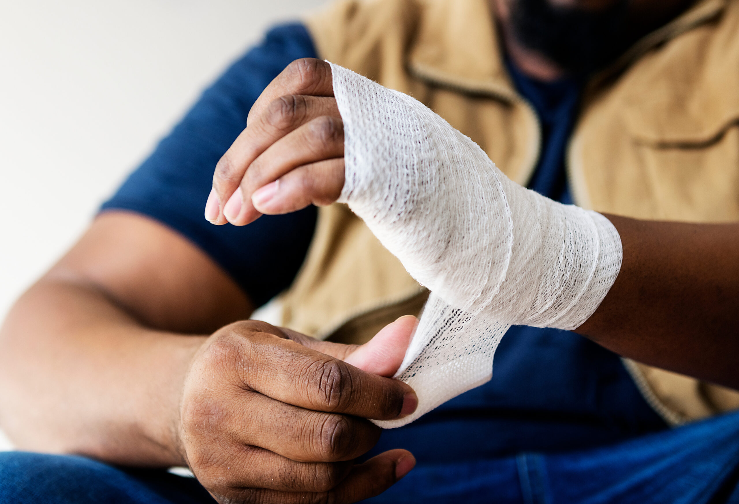 Closeup of an African-American man wrapping his own hand after a workplace injury.