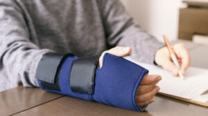 Closeup of someone in a temporary cast filling out workers' compensation paperwork