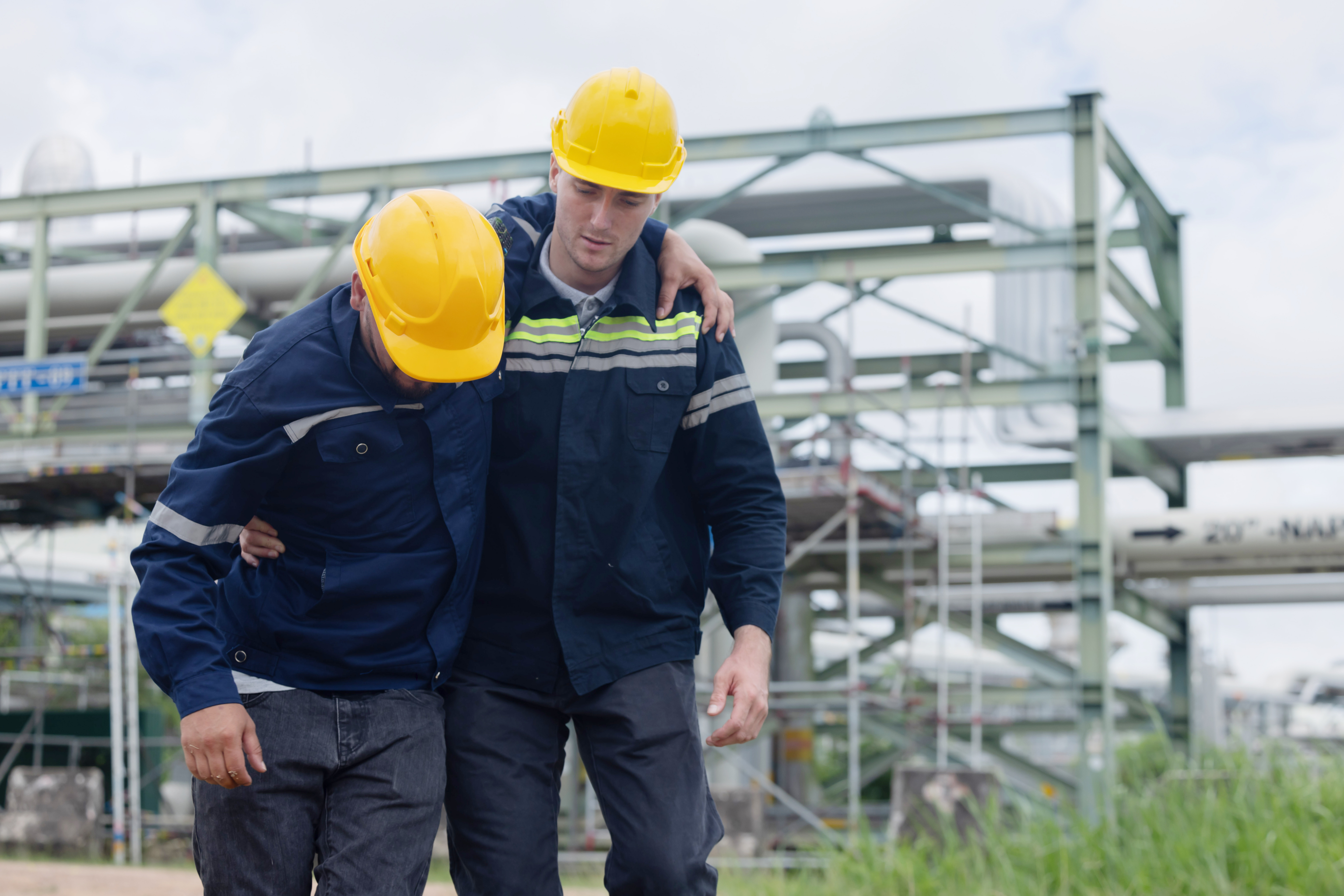 Oil refinery engineer getting first aids help from his college after get injured while working on the site