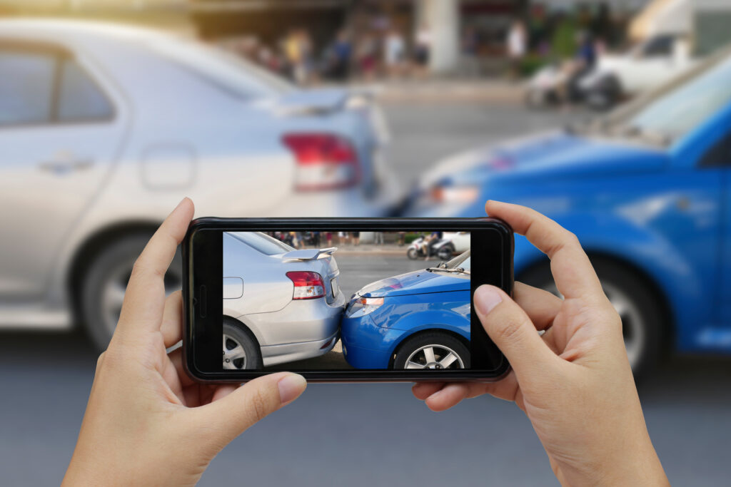 Closeup of someone taking a photo of the aftermath of a car accident on their smartphone