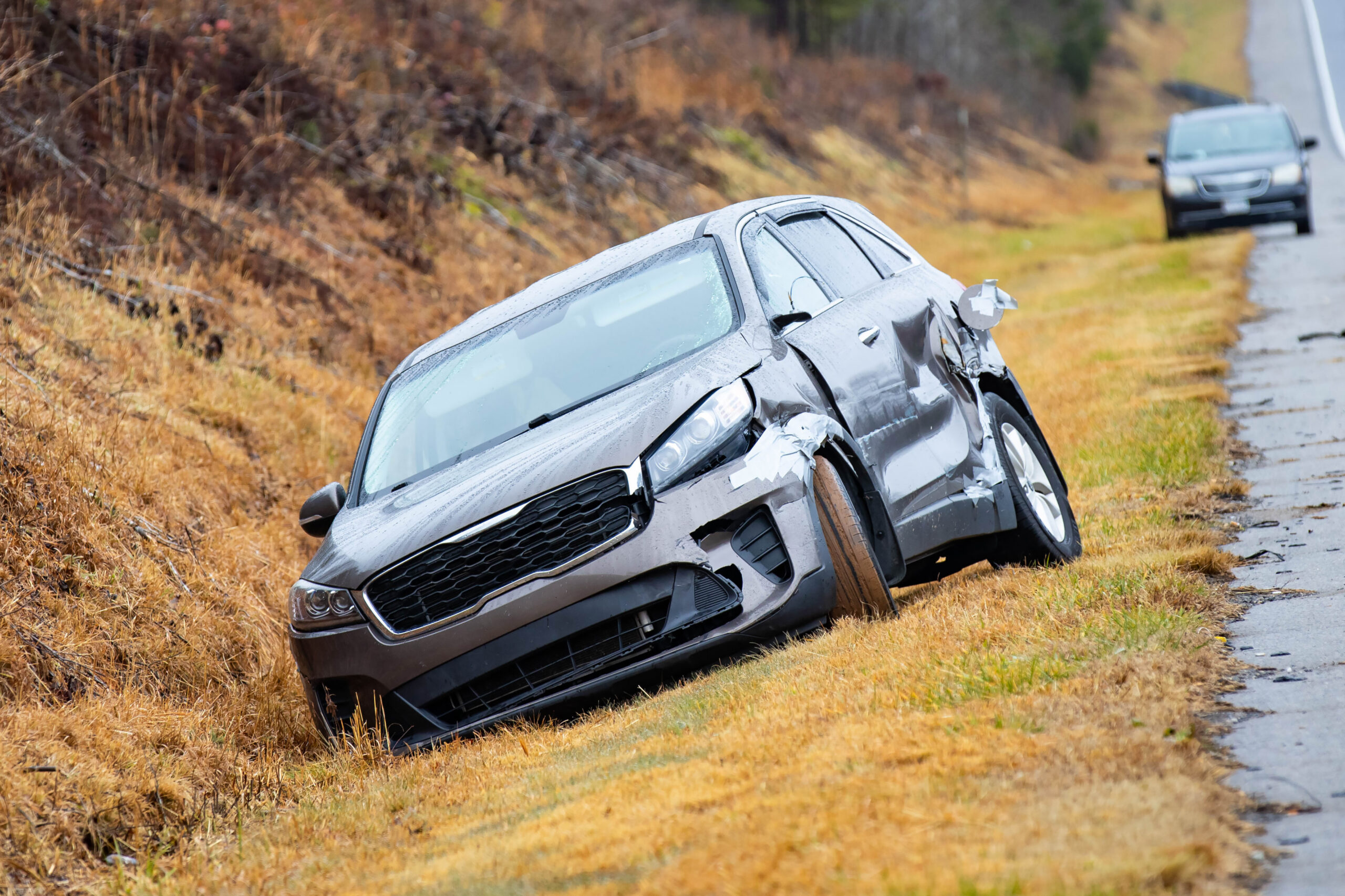 Image of a car in a ditch on the right side of a two-lane highway