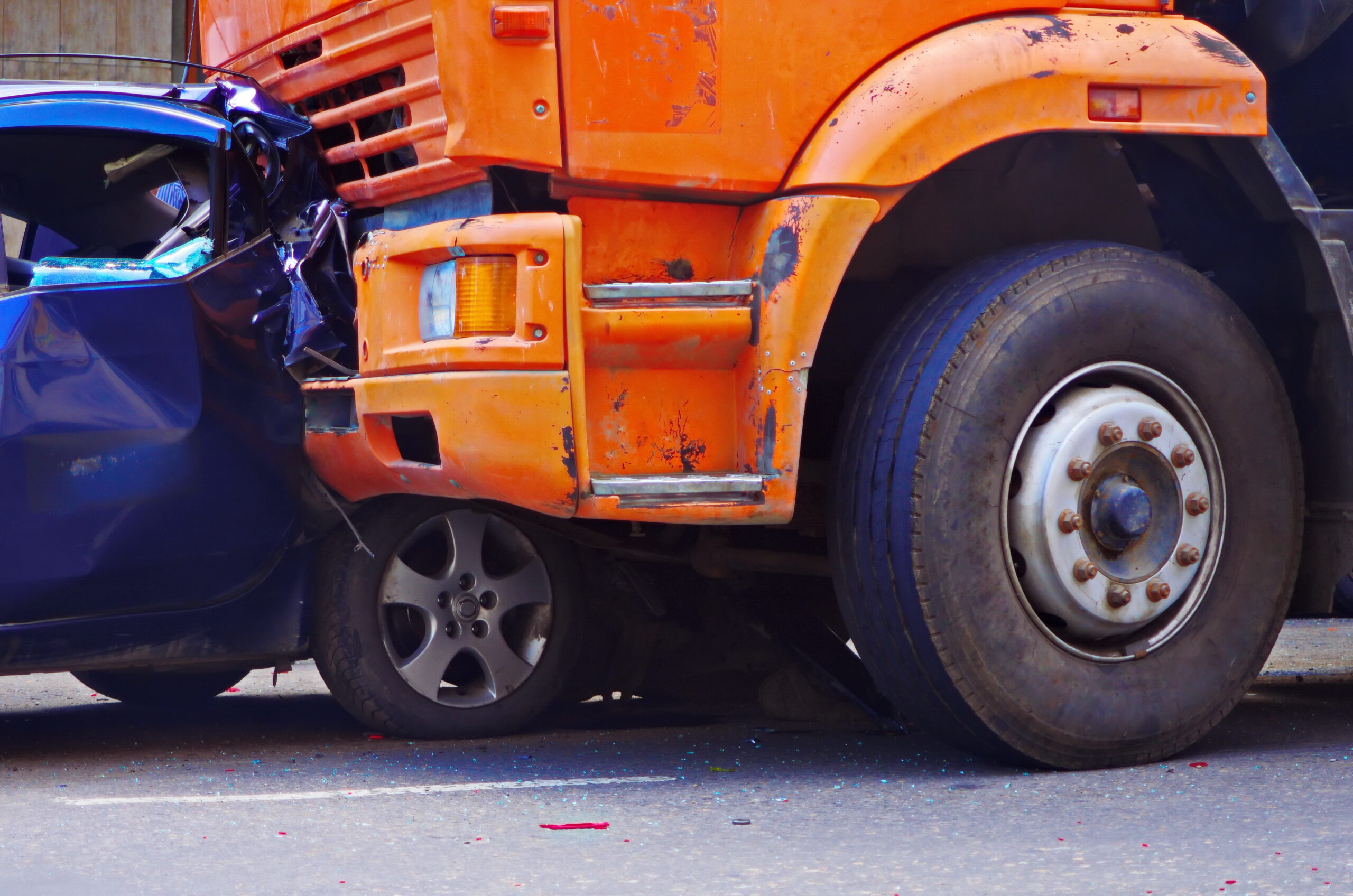 Accident involving a semi-truck and a passenger vehicle. The front of the passenger vehicle is crushed by the cab of semi-truck, indicating a head-on collision