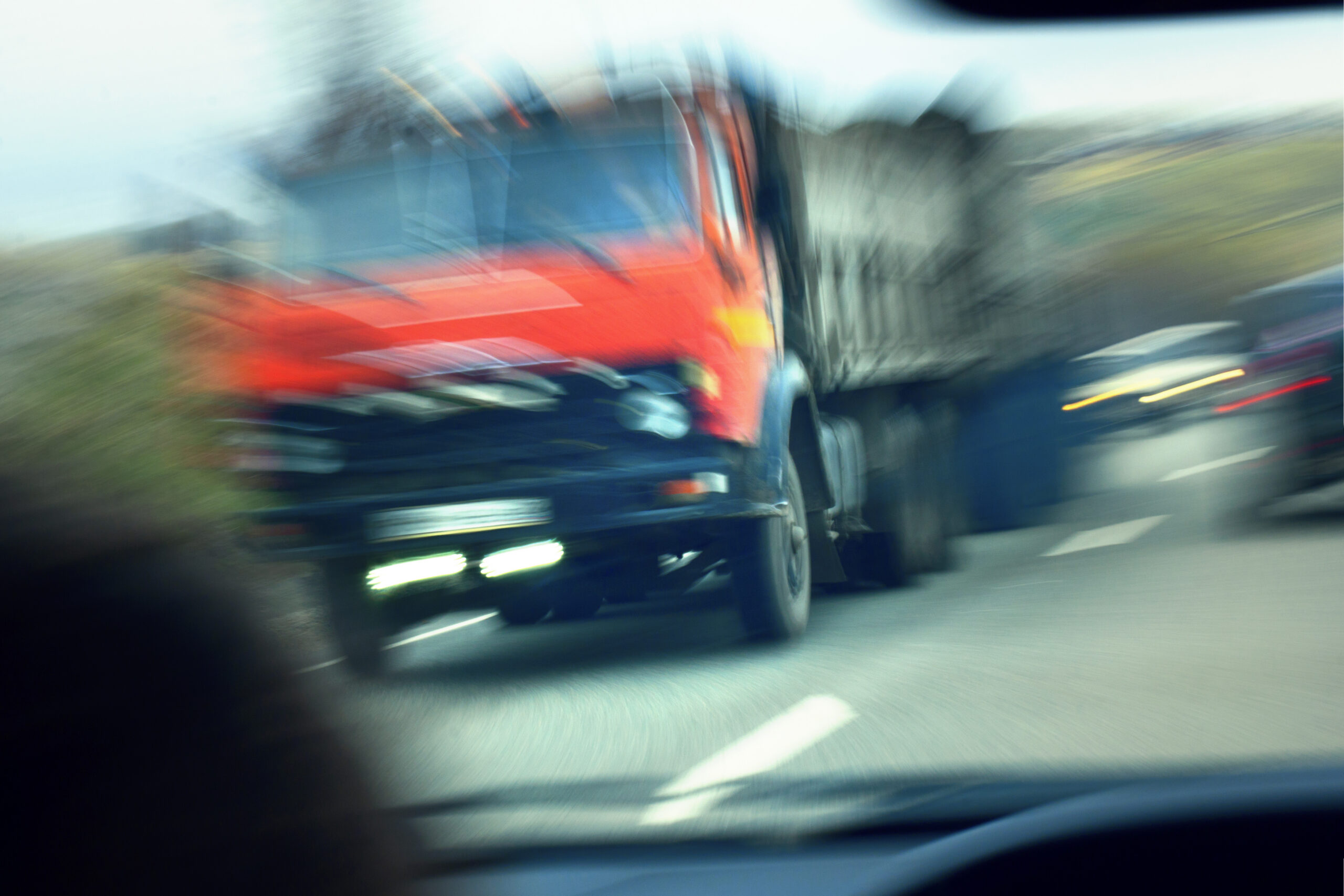 Image of a commercial truck moving on the road. The image is blurred as if to indicate there is about to be a truck accident.