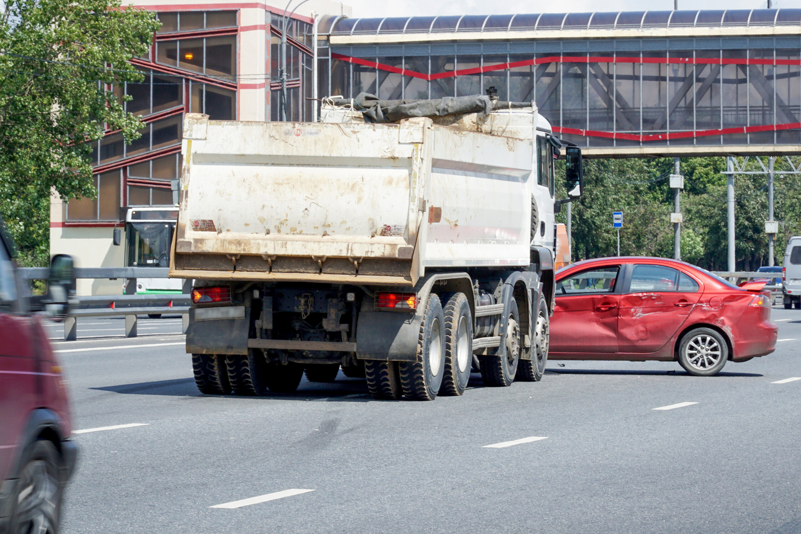 The collision of a truck and a car on a large city multi-lane road.