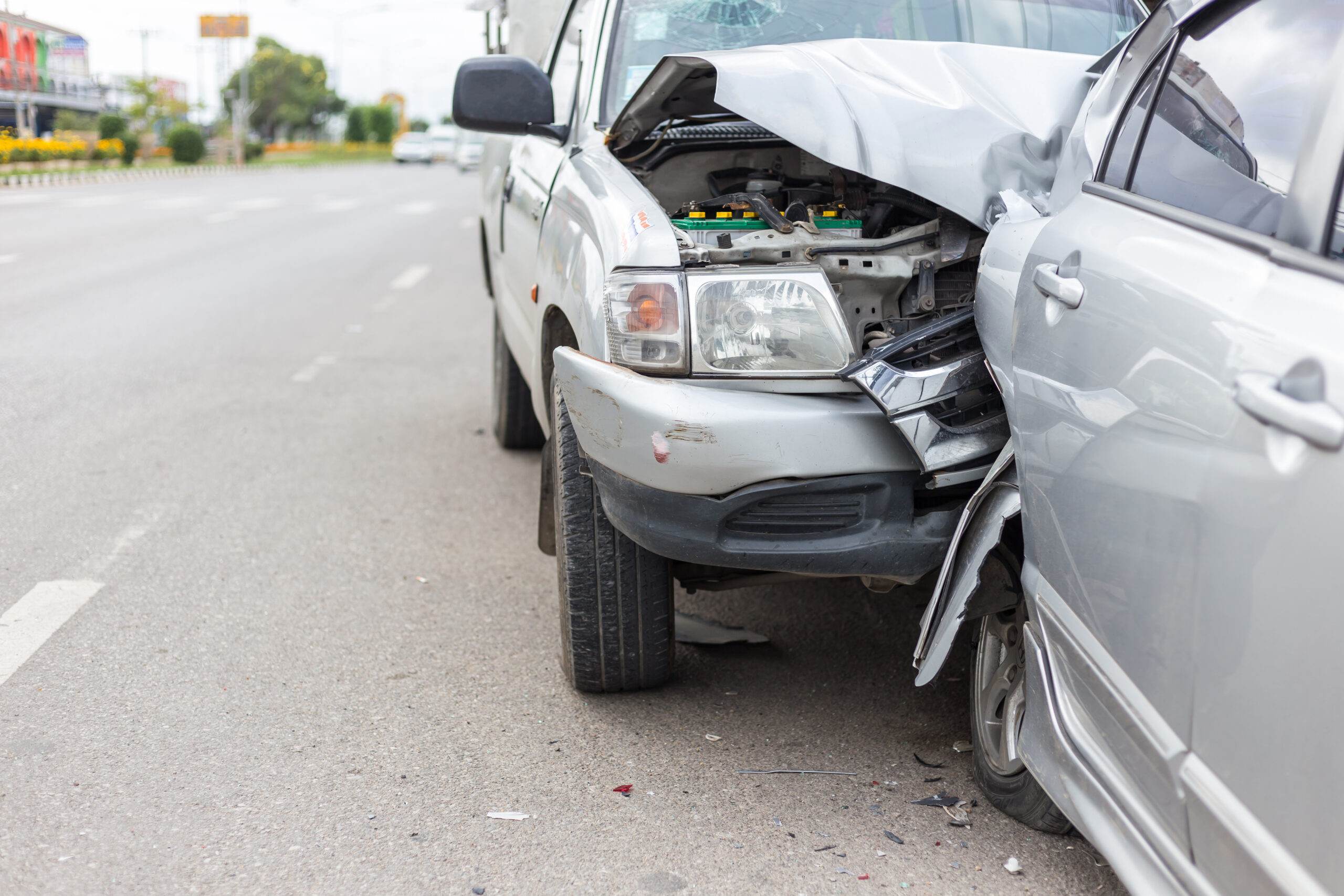 Image of a car rear-ended by a truck, both pulled over on the side of a road. Indicates a work-related car accident in Warner Robins.