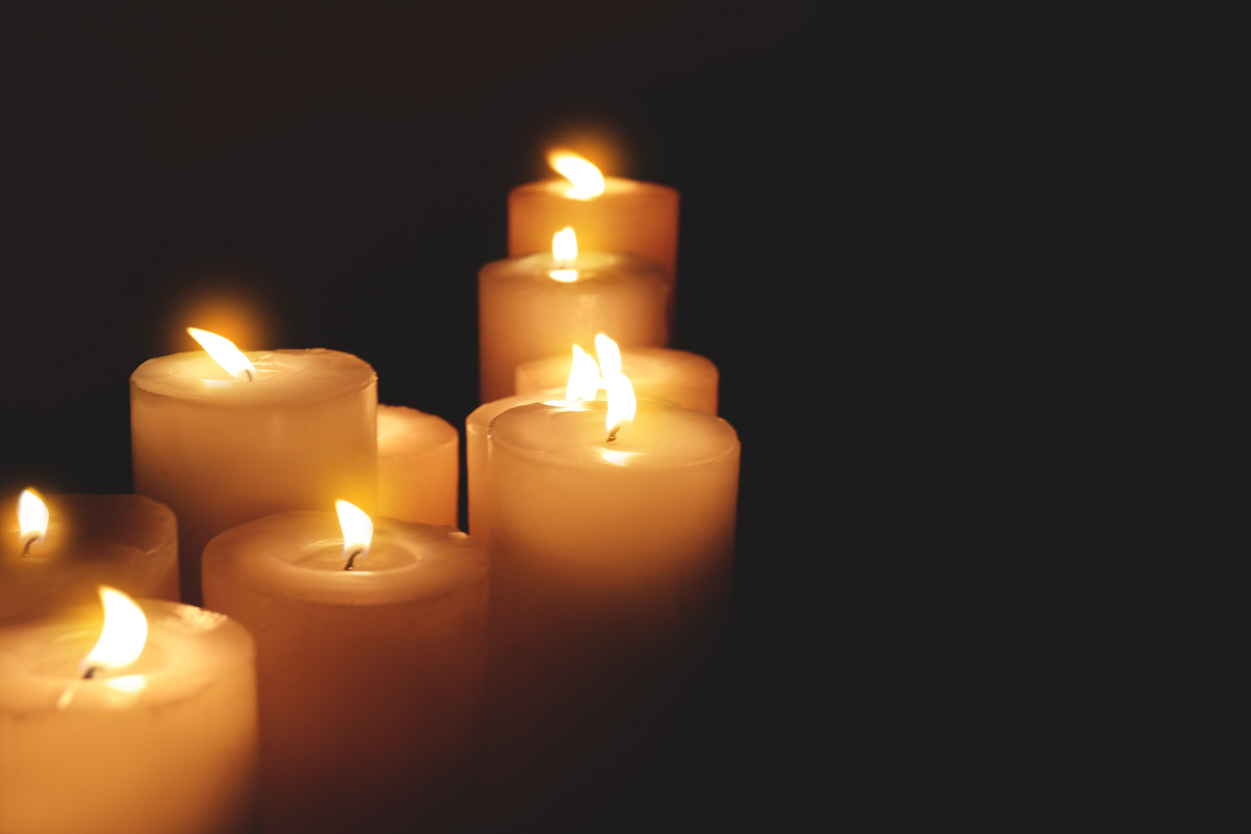 Image of several candles lit in a dark room, suggesting a funeral or memorial for a wrongful death after a workplace accident.